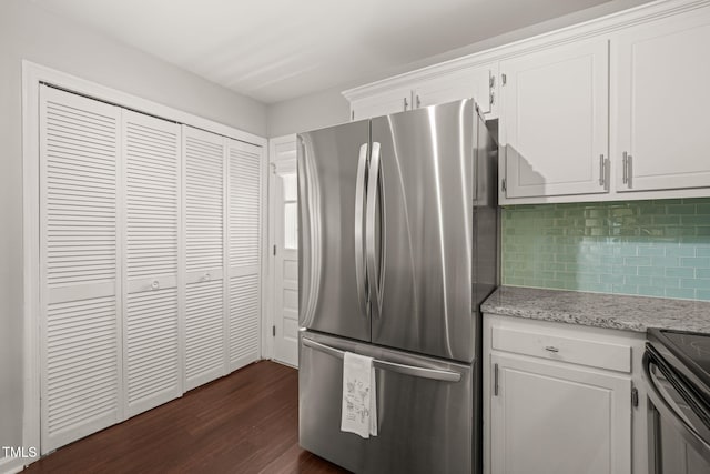 kitchen featuring dark wood-style flooring, tasteful backsplash, freestanding refrigerator, white cabinets, and light stone countertops