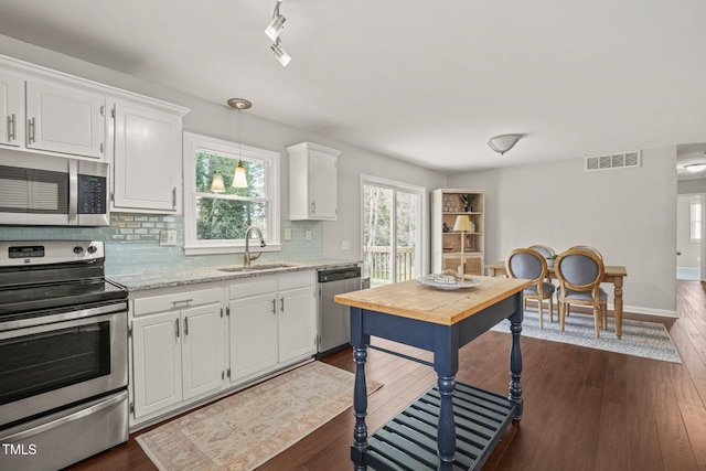 kitchen featuring decorative backsplash, dark wood finished floors, stainless steel appliances, white cabinetry, and a sink