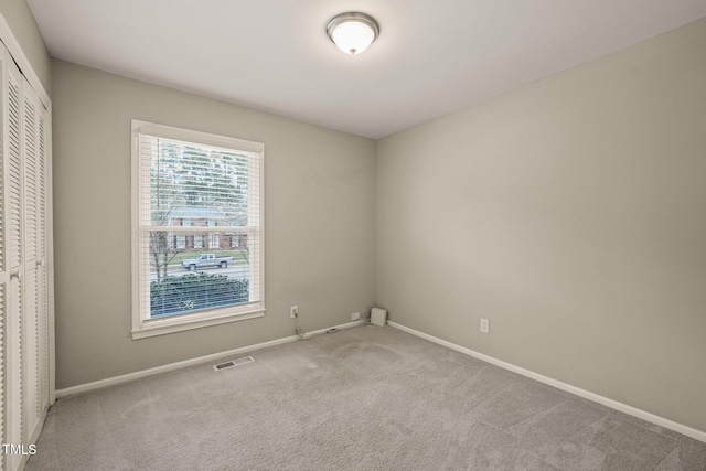 carpeted spare room featuring visible vents and baseboards