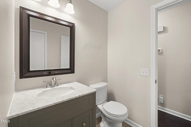 bathroom with toilet, baseboards, and vanity