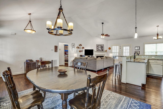 dining room featuring visible vents, ceiling fan with notable chandelier, dark wood-style floors, and vaulted ceiling