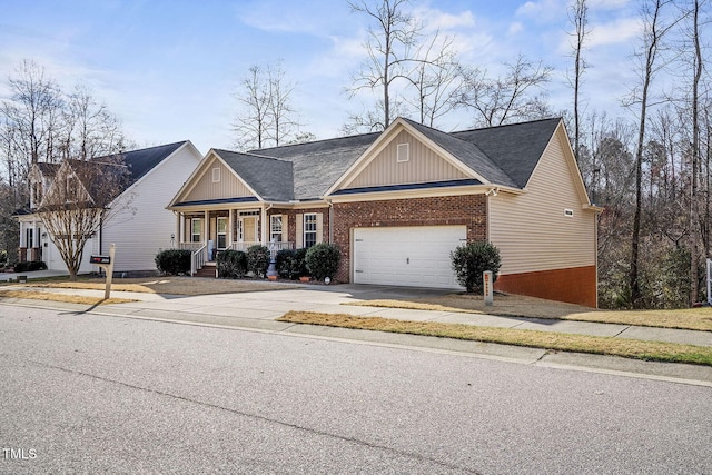 view of front facade with a porch, brick siding, an attached garage, and driveway