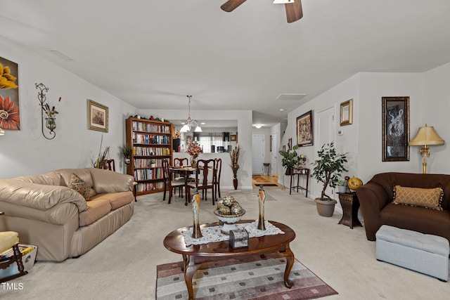 living area featuring light carpet and ceiling fan with notable chandelier