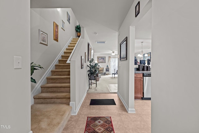 foyer entrance with light tile patterned floors, stairway, ceiling fan with notable chandelier, and baseboards