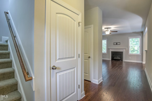 corridor featuring dark wood-type flooring, stairway, and baseboards