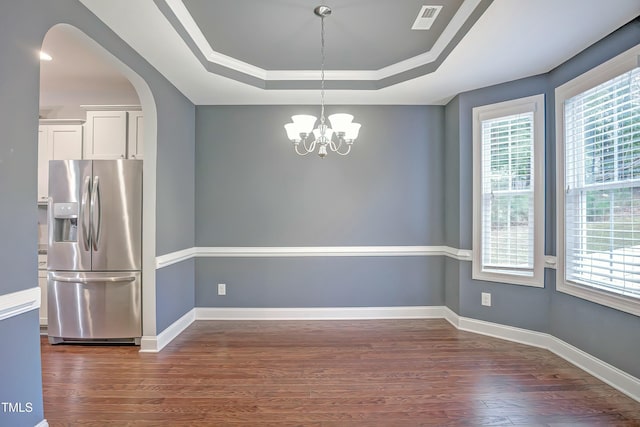 unfurnished dining area with baseboards, arched walkways, visible vents, a raised ceiling, and dark wood-type flooring