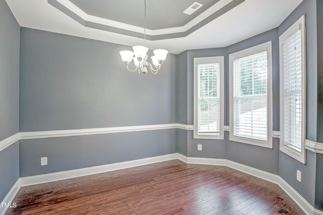 spare room with baseboards, visible vents, a raised ceiling, wood finished floors, and a chandelier