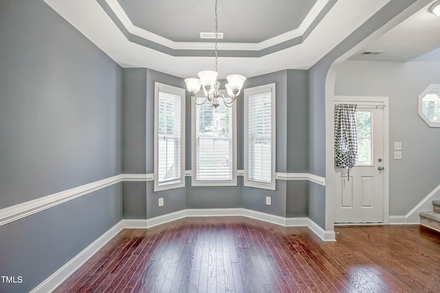 unfurnished dining area featuring a tray ceiling, baseboards, visible vents, and hardwood / wood-style floors