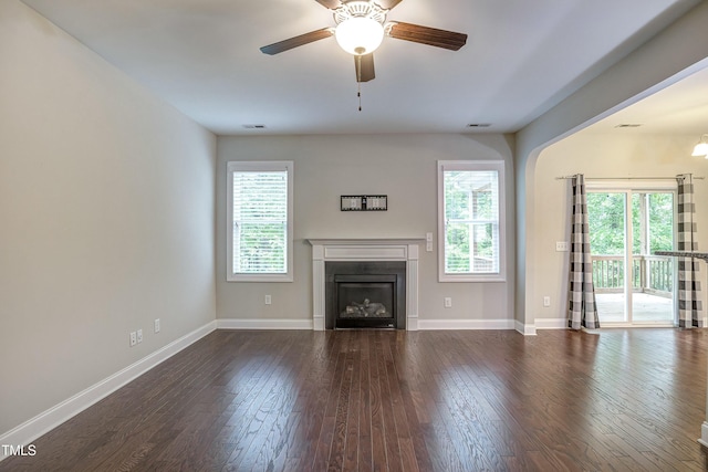 unfurnished living room with plenty of natural light, dark wood finished floors, and baseboards