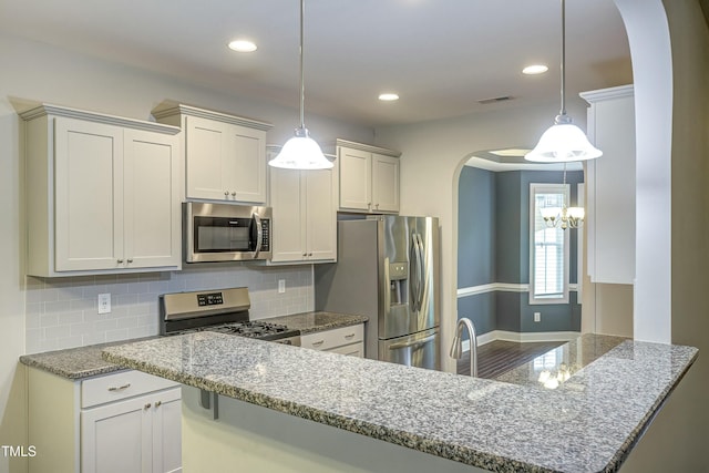 kitchen with arched walkways, stone countertops, recessed lighting, stainless steel appliances, and decorative backsplash