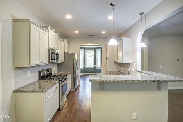 kitchen featuring arched walkways, stainless steel appliances, a breakfast bar, decorative backsplash, and dark wood-style floors