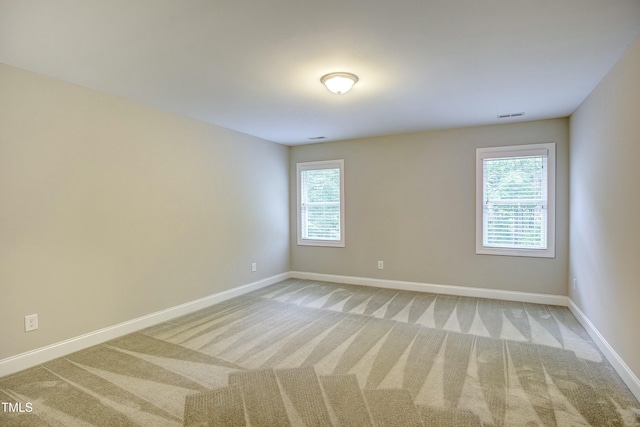 empty room featuring carpet, visible vents, and baseboards