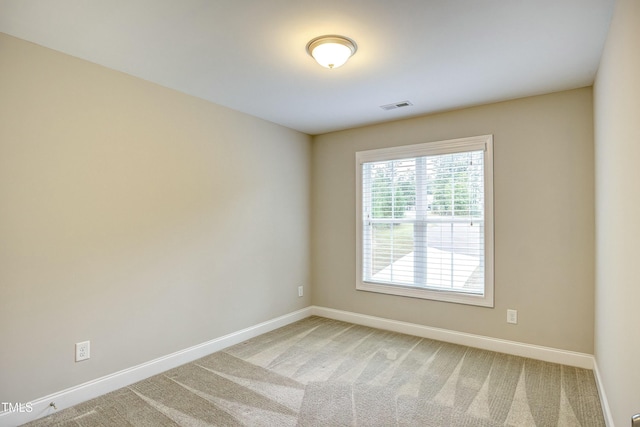 spare room with light colored carpet, visible vents, and baseboards