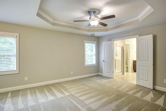 unfurnished bedroom featuring ornamental molding, a tray ceiling, baseboards, and light colored carpet