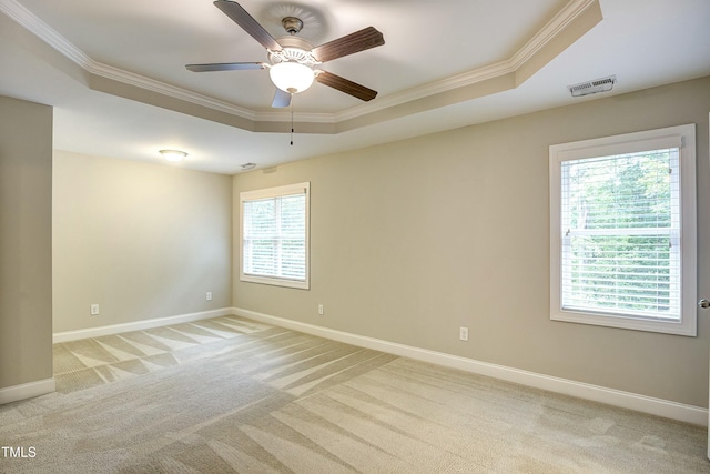 spare room featuring light colored carpet, a tray ceiling, visible vents, and crown molding