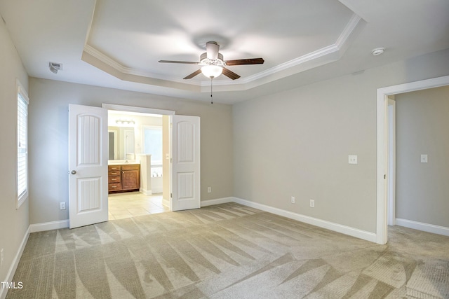 unfurnished bedroom with baseboards, a tray ceiling, crown molding, and light colored carpet