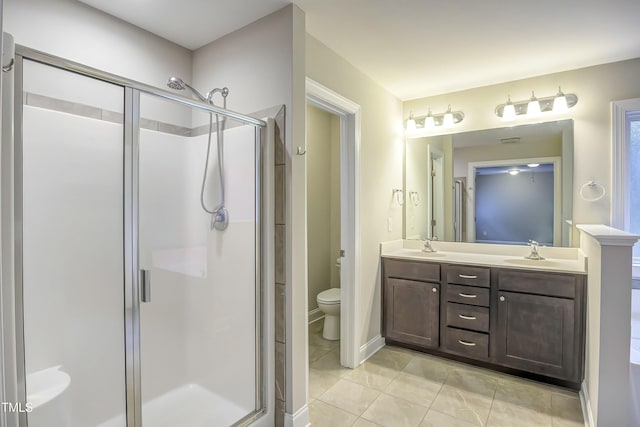 full bath with toilet, a sink, a shower stall, tile patterned floors, and double vanity