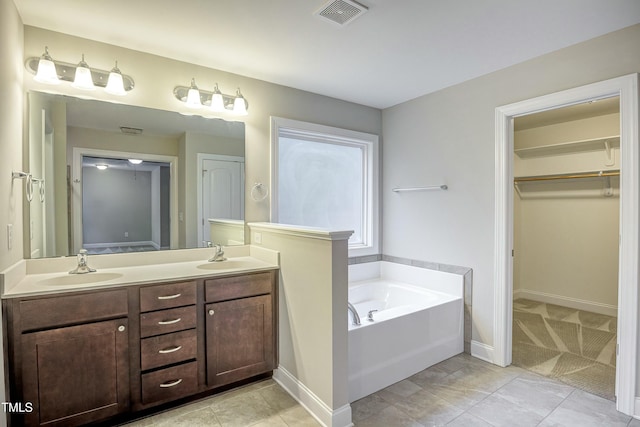 bathroom featuring a bath, double vanity, visible vents, and a sink