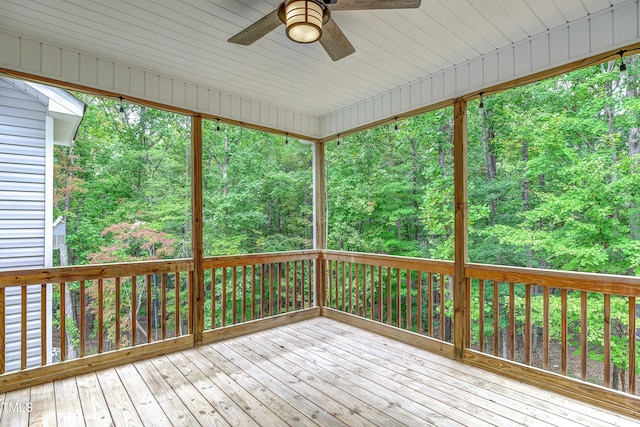 wooden terrace with ceiling fan and a view of trees