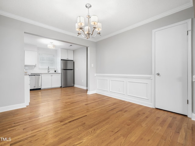 unfurnished dining area with crown molding, a sink, light wood-style flooring, and a notable chandelier