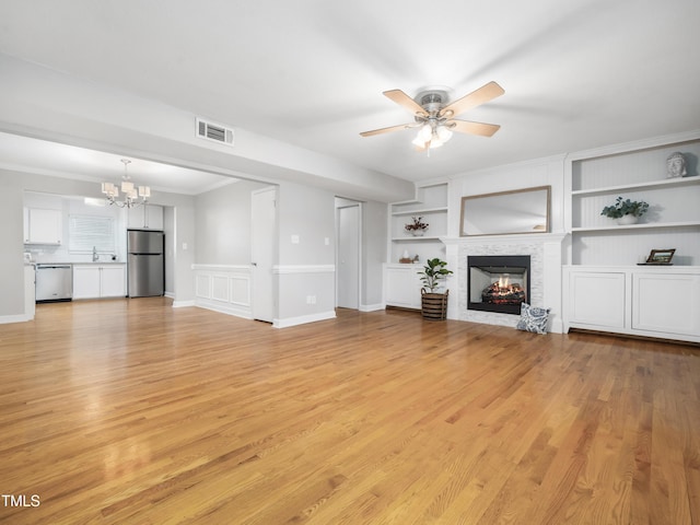 unfurnished living room with light wood-type flooring, built in shelves, a fireplace, and visible vents