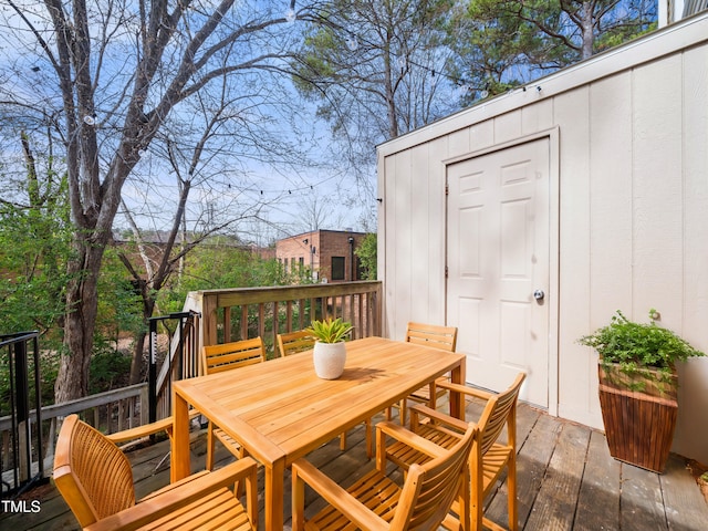 wooden deck with an outbuilding, a storage unit, and outdoor dining area