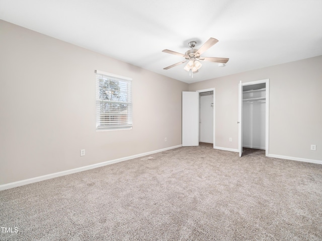 unfurnished bedroom with a ceiling fan, carpet, baseboards, and two closets