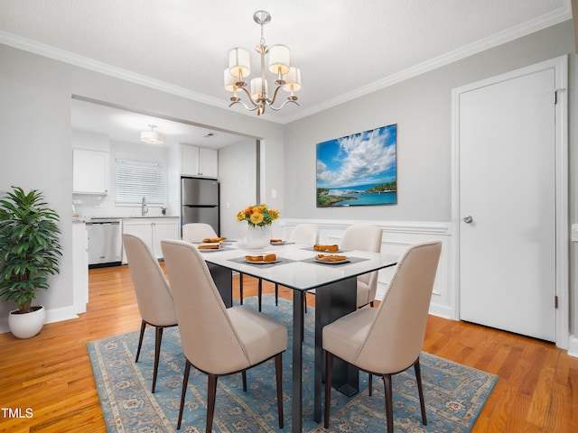 dining space featuring ornamental molding, light wood-style flooring, and an inviting chandelier