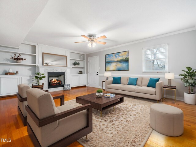 living area with built in shelves, a multi sided fireplace, and wood finished floors