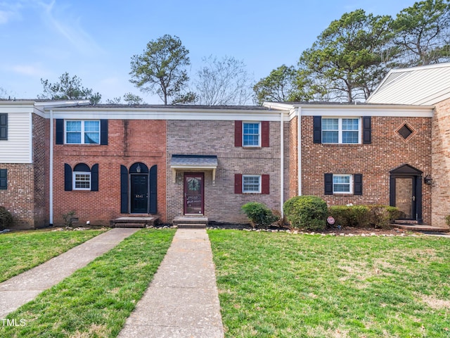 townhome / multi-family property featuring a front yard and brick siding