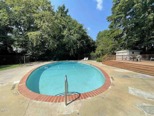 outdoor pool featuring fence and a deck