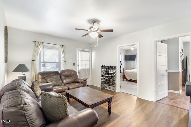 living room featuring baseboards, a ceiling fan, and wood finished floors