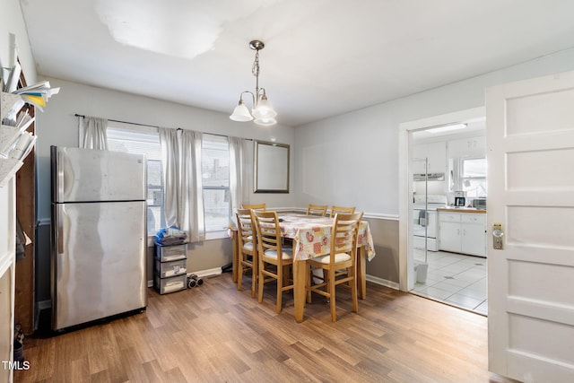 dining area featuring light wood-type flooring, an inviting chandelier, and baseboards