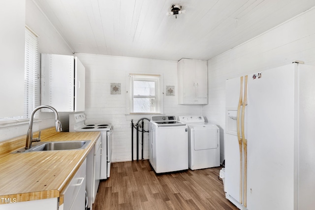 kitchen featuring white appliances, wood finished floors, a sink, white cabinets, and independent washer and dryer