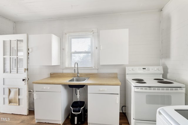 kitchen featuring dark wood-type flooring, a sink, white cabinetry, light countertops, and white range with electric cooktop