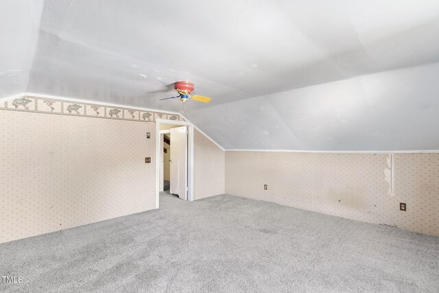additional living space with wallpapered walls, carpet, vaulted ceiling, and a ceiling fan