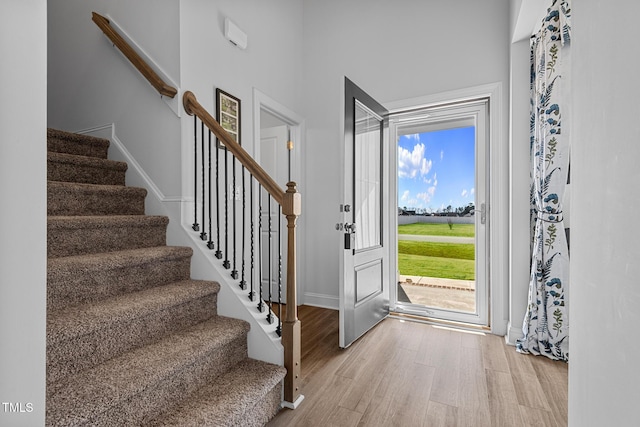 foyer entrance with light wood-style floors, baseboards, and stairs