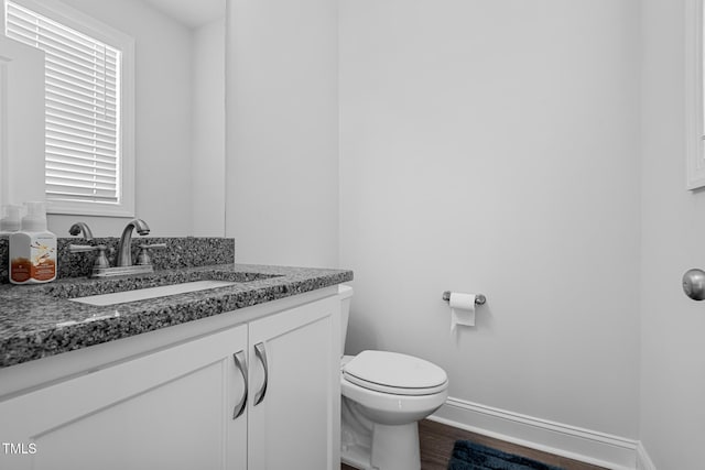 bathroom featuring baseboards, vanity, toilet, and wood finished floors