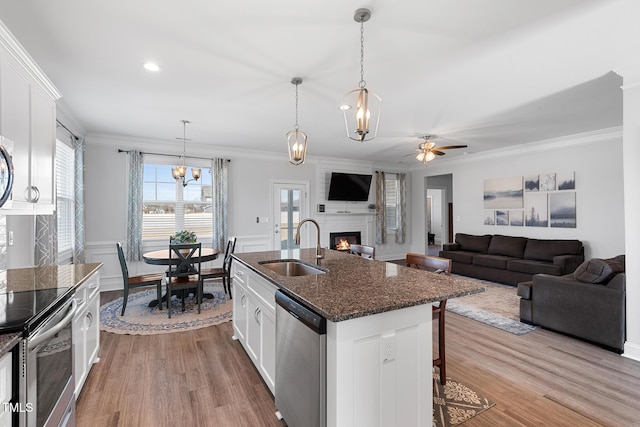 kitchen with stainless steel appliances, a breakfast bar, a fireplace, a sink, and white cabinets