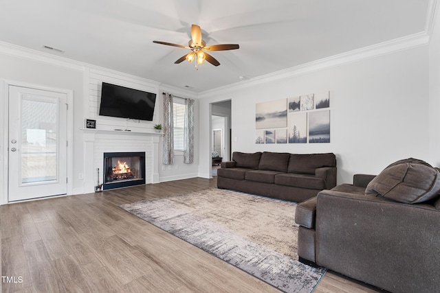 living area featuring ornamental molding, a fireplace, wood finished floors, and visible vents