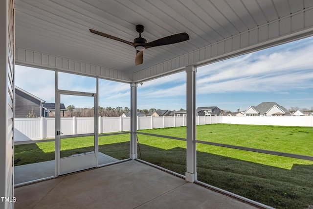 unfurnished sunroom with a residential view and a ceiling fan