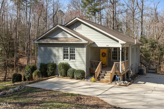 view of front facade with covered porch, central AC unit, and roof with shingles