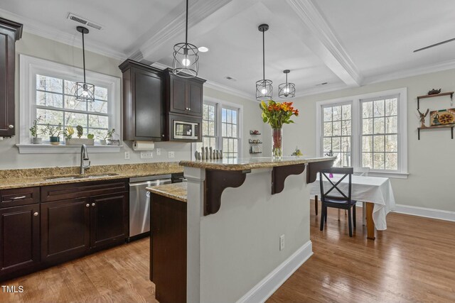 kitchen with a sink, a kitchen breakfast bar, dishwasher, and light wood-style flooring