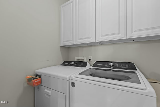 clothes washing area with washer and clothes dryer and cabinet space