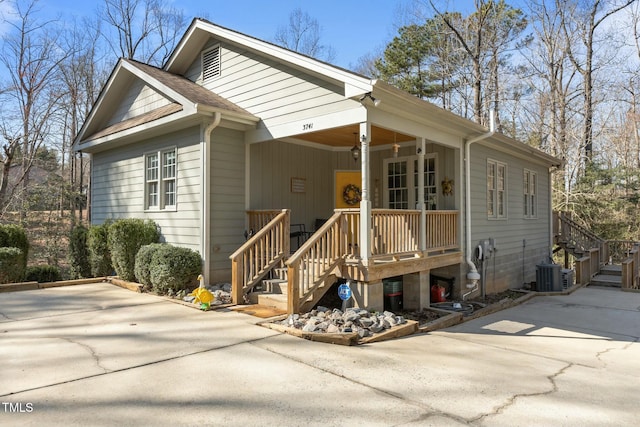 view of front of home featuring central AC unit, roof with shingles, covered porch, and concrete driveway