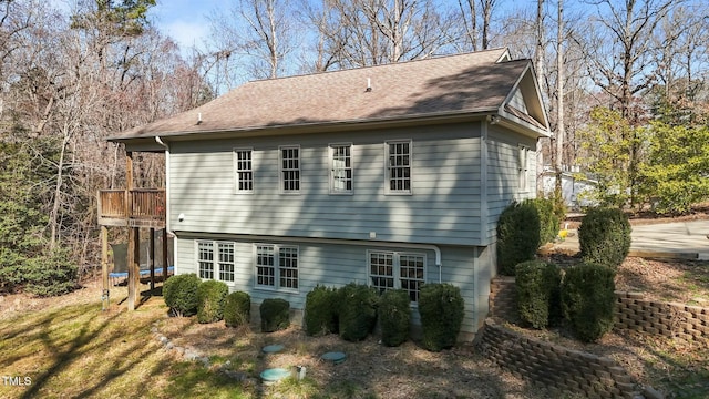 rear view of property with a trampoline and a shingled roof