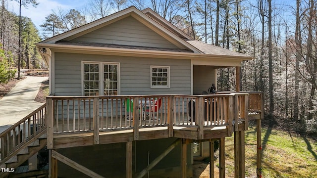 back of property with a deck, stairs, and roof with shingles