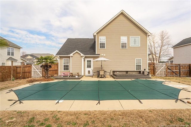 back of property with a fenced backyard, a gate, a fenced in pool, and a patio