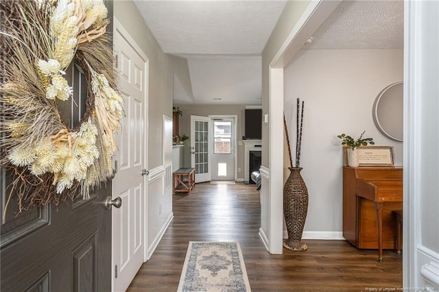 foyer with dark wood-style flooring, a fireplace, a textured ceiling, and baseboards