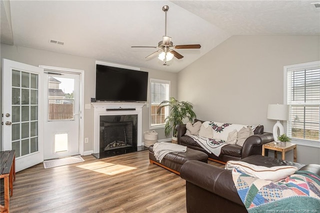 living room with plenty of natural light, visible vents, vaulted ceiling, and wood finished floors